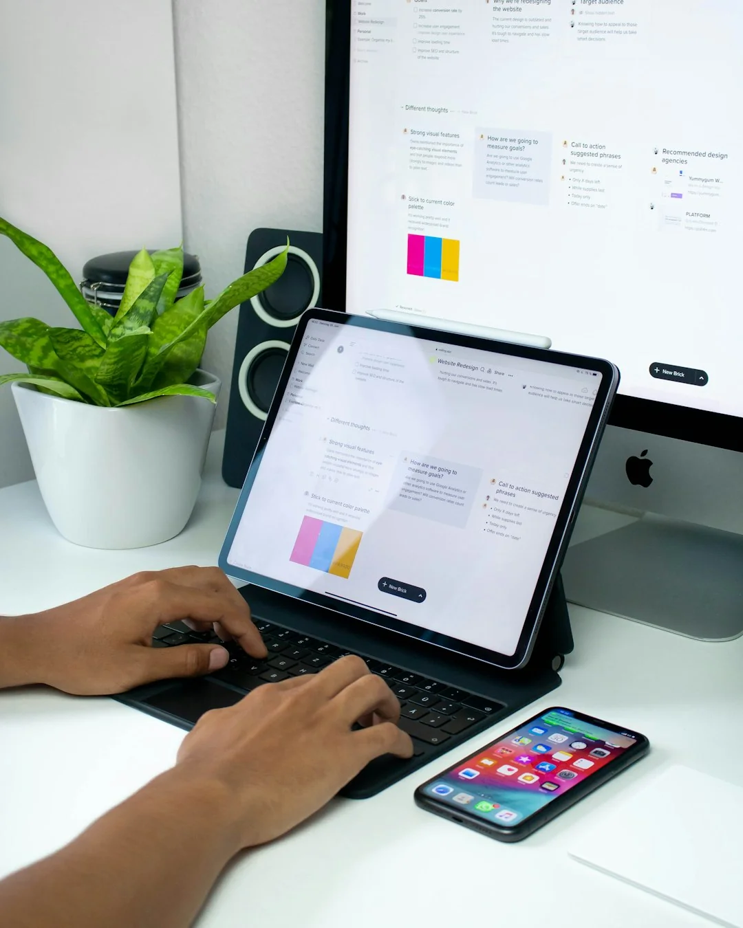 Une personne navigue sur le web sur un MacBook posé sur un bureau en bois, avec un smartphone.